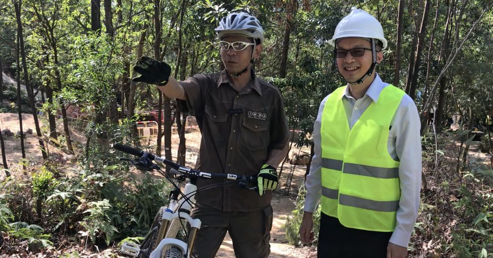 The trail specialist of the International Mountain Bicycling Association, Mr H.M. LIM (left), shows USDEV, Mr LIU Chun-san (right), that the mountain bike training ground provides trails of different riding difficulties and features for mountain bikers to choose routes that suit them best.