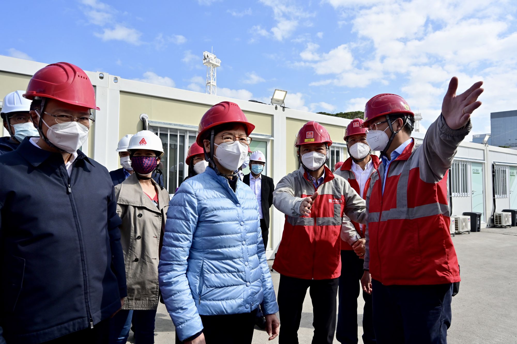 The Chief Executive, Mrs Carrie LAM, visited the community isolation facility (CIF) in Tsing Yi constructed with the Mainland’s support earlier on (28 February). Photo shows Mrs Carrie LAM (front, second left), accompanied by the Chairman and Non-executive Director of the China State Construction International Holdings Limited, Mr YAN Jianguo (front, second right), was briefed by a staff member of the contractor on the facilities. Beside her is the Deputy Director of the Liaison Office of the Central People’s Government in the Hong Kong Special Administrative Region, Mr CHEN Dong (front, first left).