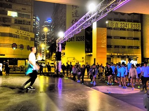An instructor does warm-up exercises with more than a hundred night runners wearing fluorescent accessories
