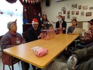 廖振新副局長（左二）與「老友記」玩「聖誕傳愛心」禮物傳送遊戲，並與長者傾談。