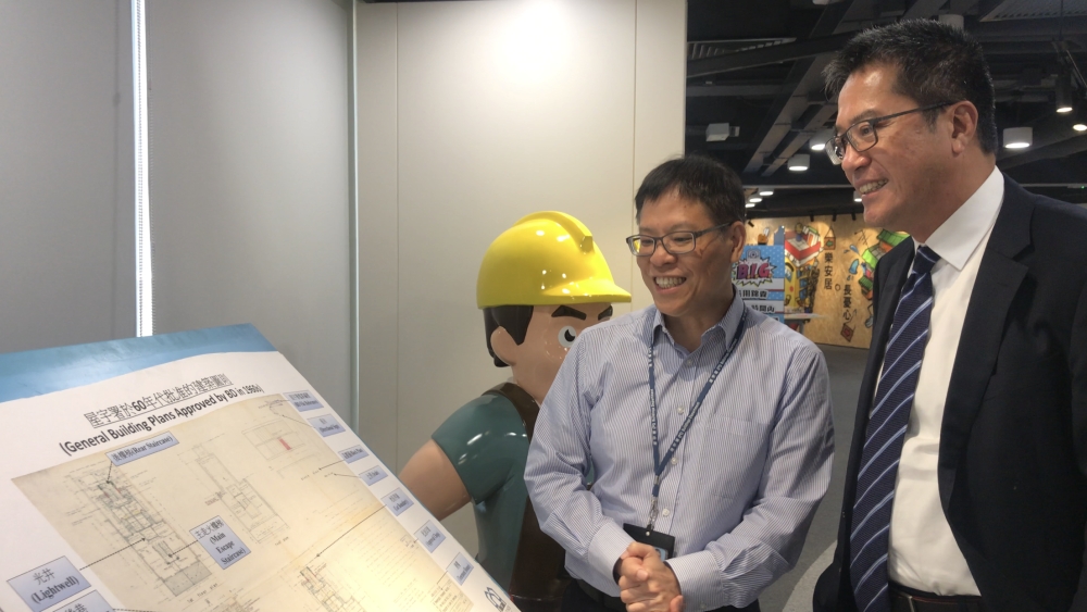 屋宇署副署長余德祥（左）向黃偉綸局長展示60年代的批准建築圖則。