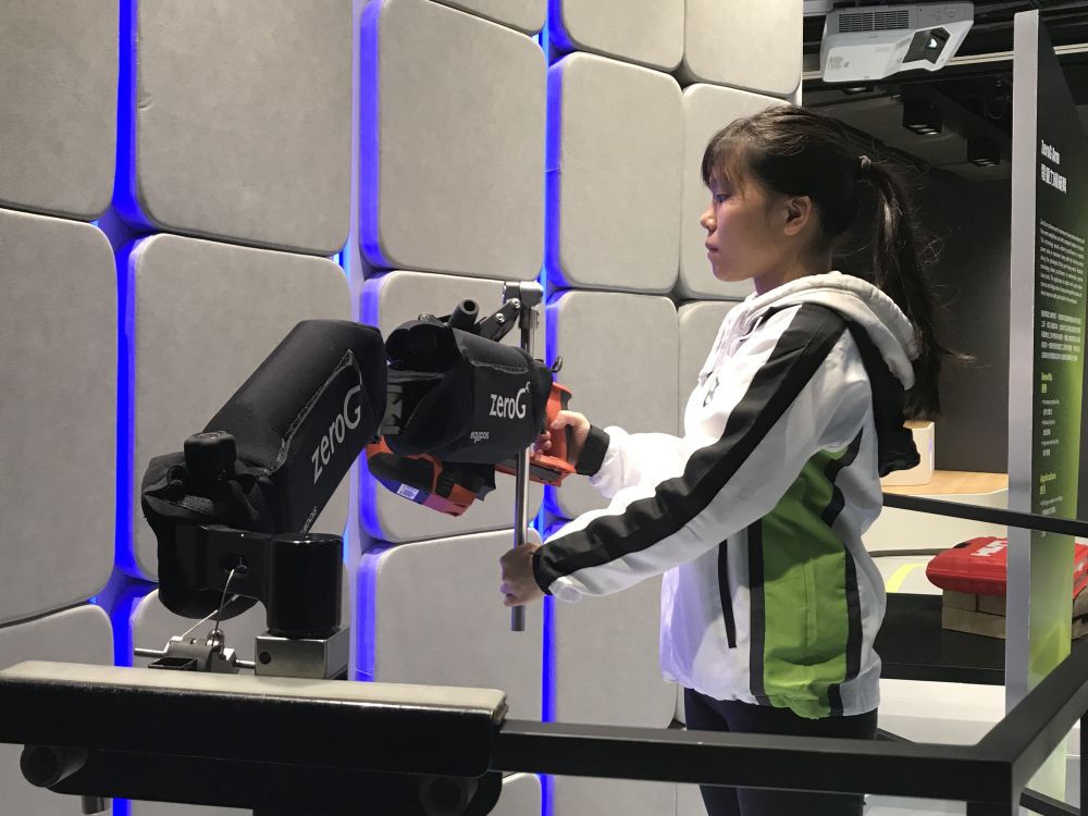 A staff member of the Centre demonstrates how to use Zero G arms to comfortably operate heavy tools and hence improve occupational safety.