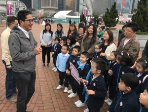 Mr Michael WONG, SDEV; Mr LIU Chun-san, Under Secretary for Development (USDEV); Mr Allen FUNG, Political Assistant (PA) to SDEV, together with kindergarten children and their parents, posing for a group photo in front of the Observation Wheel at the Central Harbourfront.
