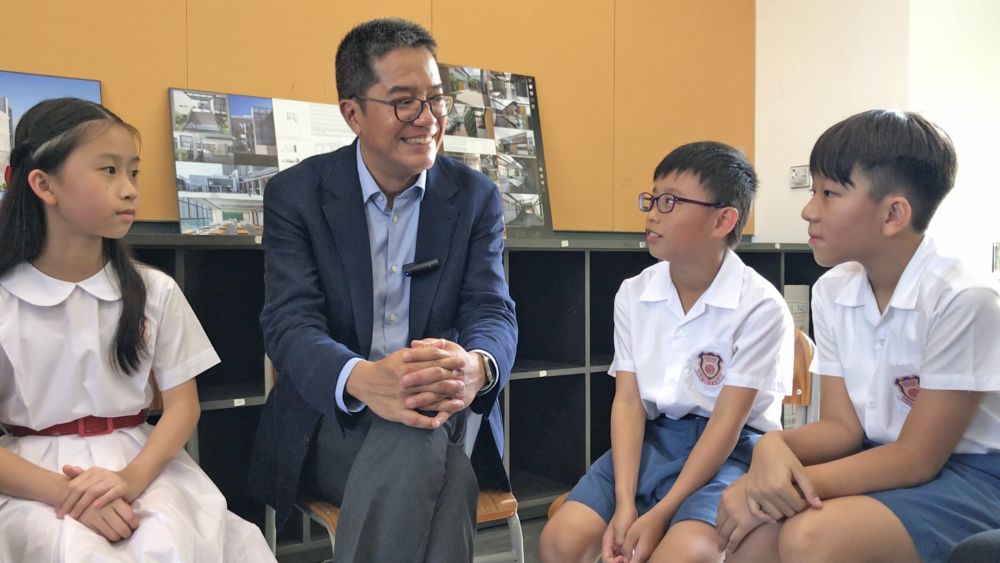 Three primary school students say that they like the school environment very much, especially the library and the luxuriant lawn.
