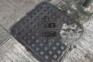 The two small sealing plugs on the manhole cover help prevent a lady’s high-heel shoes from getting stuck in the keyholes or the breeding of mosquitoes arising from accumulation of water.