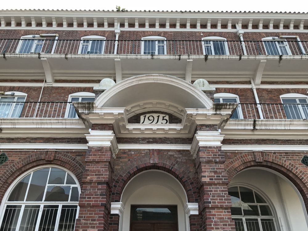 Red brick is the main material of the Eliot Hall and May Hall with a rich variety of architectural elements, such as the curved pediments (hoods) over the entrance doorways and Doric capitals of the May Hall shown in the picture, which were widely adopted in the Edwardian period in England.