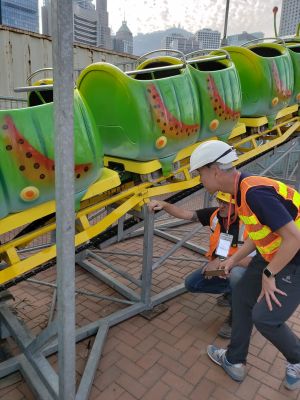 A colleague of the EMSD is overseeing the non-destructive test of the amusement ride by monitoring the surveyors on conducting the tests on critical welds in order to ensure that the rides can bear the sress and loading.
