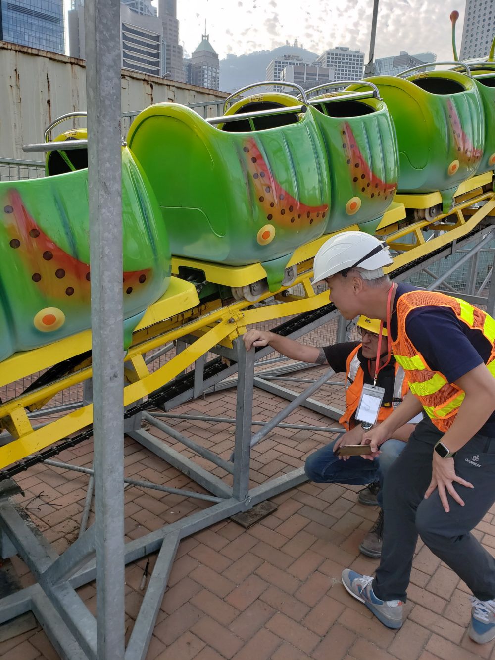A colleague of the EMSD is overseeing the non-destructive test of the amusement ride by monitoring the surveyors on conducting the tests on critical welds in order to ensure that the rides can bear the sress and loading.