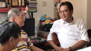 The flat owner Mr LAM (centre) tells Mr Michael WONG, the SDEV (right), that the application procedures for BMGSEO are simple and easy. He has made use of the full grant of $40 000 under the scheme to substantially improve their living environment.