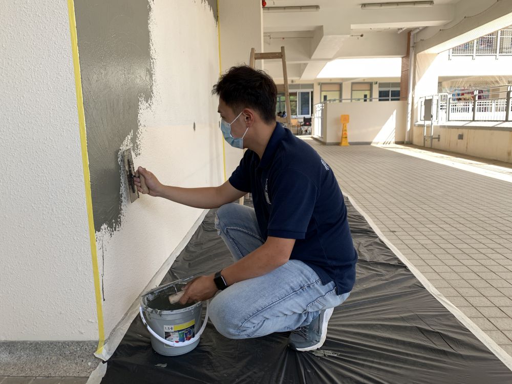 Will is the person-in-charge of a decoration works company. Outside working hours, he takes part in voluntary services. In the picture, he is setting up an easy-care craft wall invented by him in a special school. Students can draw and write graffiti on the wall to bring their creativity into play.