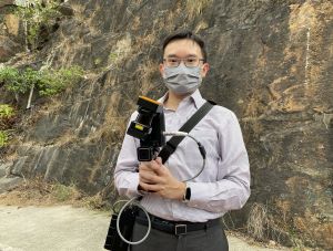 Geotechnical Engineer of the GEO, Mr LEUNG Wai-kin, introduces us to the laser scanner he is holding, saying that the data collected by the scanner can form a 3D topographical model on a computer monitor, which can help the department assess landslide risks.
