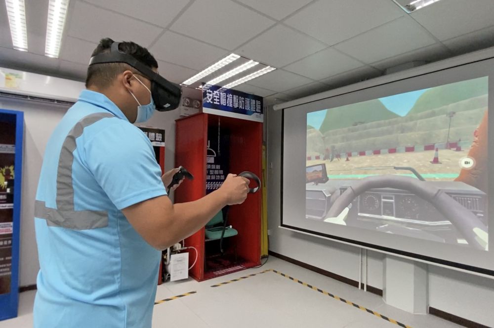 前线员工郑祖卫示范利用虚拟实境（Virtual Reality, VR）学习操作机械的情况。