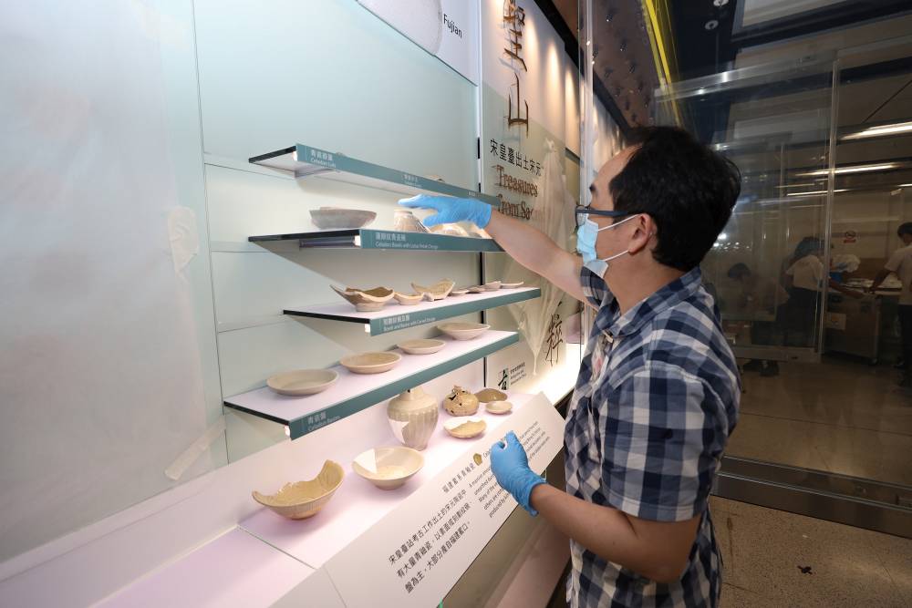 AMO colleagues carefully put the artefacts into the display cabinet.