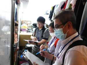 手持文件夾的水務署與差餉物業估價署同事採取跨部門聯合行動，探訪「劏房」租戶，了解他們有否被濫收水費及宣傳有關法例的要求。