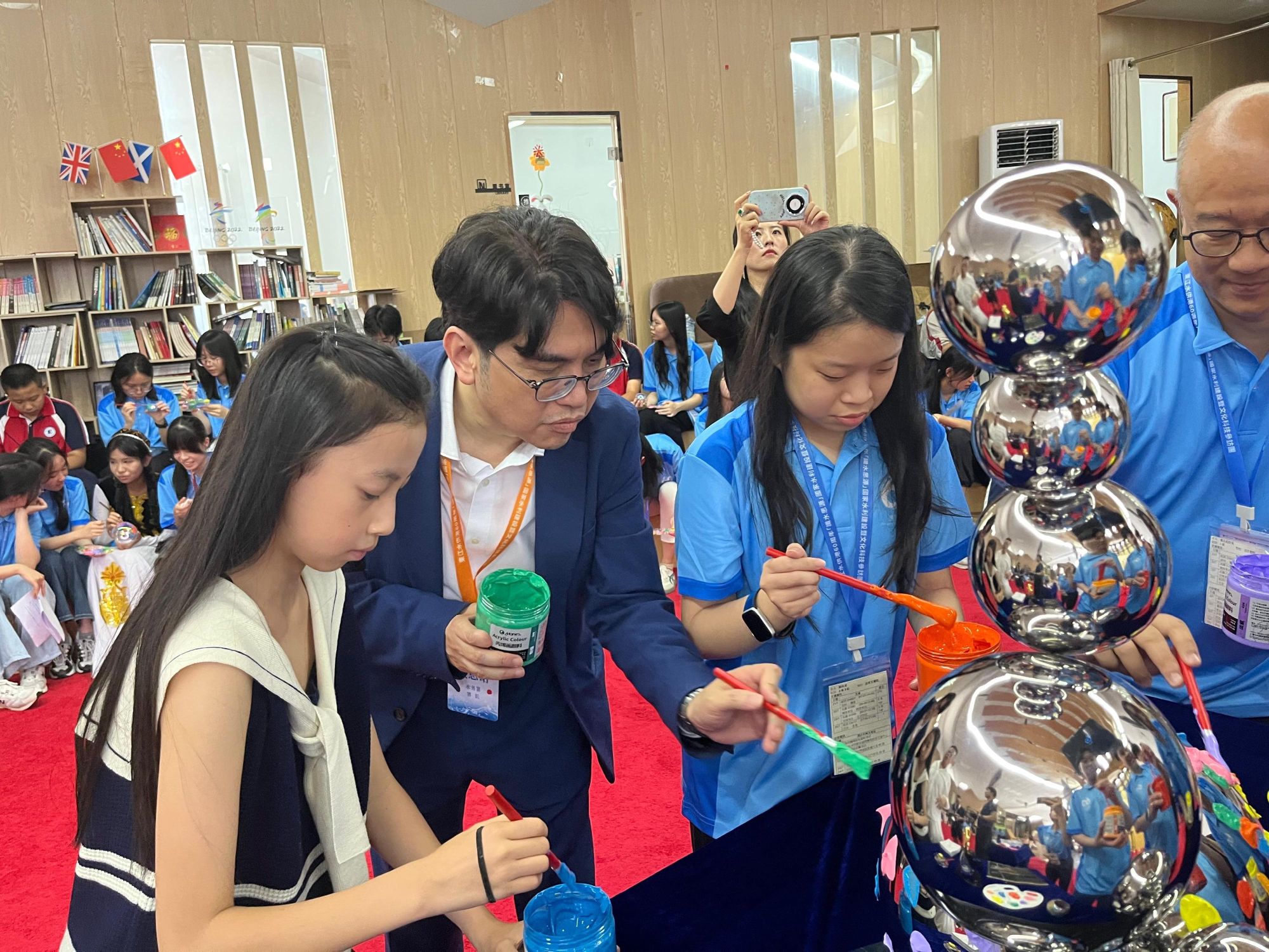 圖示參訪團中學生團員與當地的中學生進行互動交流，並一同參與以東江水為主題的藝術裝置創作。水務署署長黃恩諾（左二）參與其中。