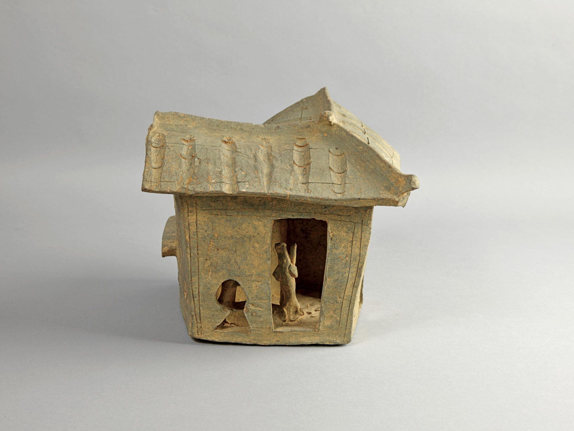 李鄭屋漢墓出土曲尺式陶屋模型，屋後設小院圈養牲畜，屋內有人舂米，婦人抱子，是漢代百姓生活的寫照。（古物古蹟辦事處藏）