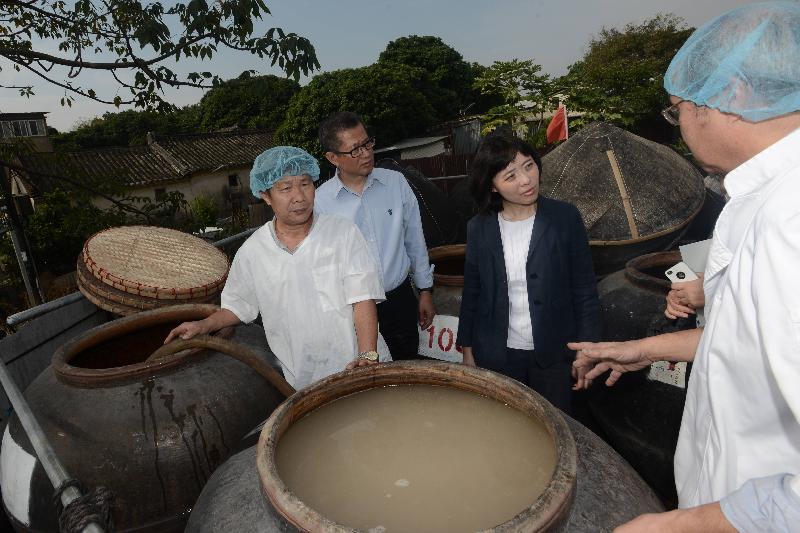 Mr Chan (second left) tours a soy sauce factory in Shek Tsai Leng to learn about its daily operation..