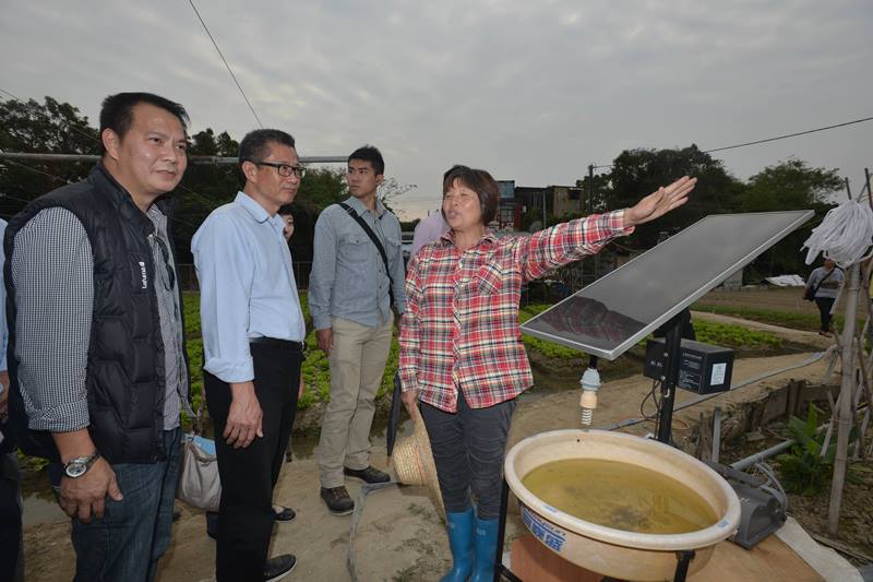 A farmer explains to Mr Chan (second left) a solar powered device..