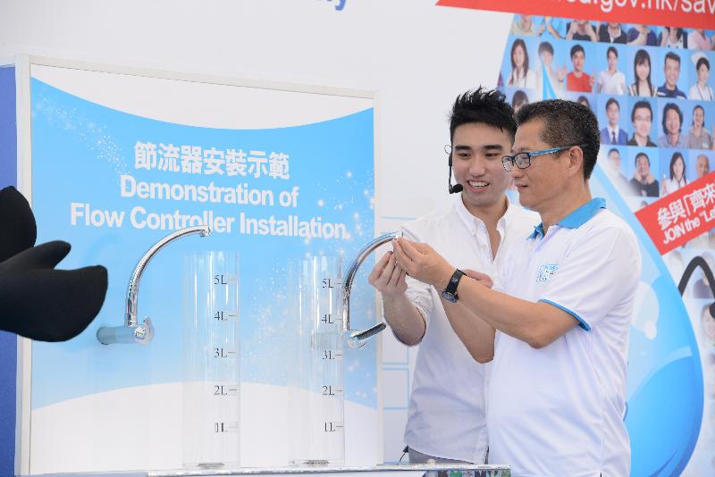 Mr Chan (first right) shows how to install a flow controller on a water tap.
