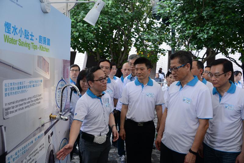 Mr Chan (second right), Mr Wai (first right) and Mr Lam (third right) tour the (Let's Save 10L Water) Campaign exhibition booths with other guests.