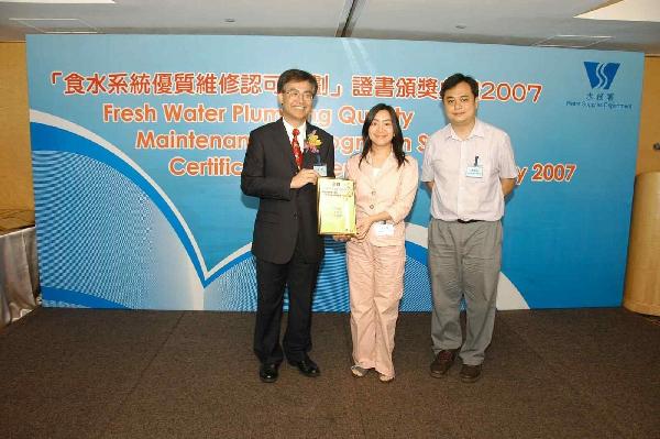 Chairman of the Advisory Committee on the Quality of Water Supplies, Professor Ho Kin-chung (left), presents a certificate to representatives from one of the qualified buildings.