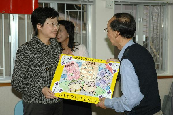 During her visit today (November 26), the Secretary for Development, Mrs Carrie Lam, met with a group of elderly building owners living in the Kwai Chung area and listened to their difficulties in carrying out proper maintenance works to their premises and buildings. After the meeting, a representative from the group presented a drawing to Mrs Lam.