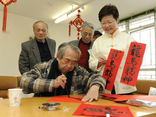 The Secretary for Development, Mrs Carrie Lam, watching an elderly writing spring couplets.