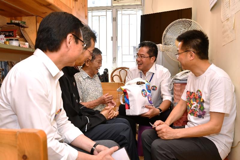 Accompanied by the Chairman of the Sham Shui Po District Council, Mr Ambrose Cheung (second left), the Secretary for Development, Mr Michael Wong (second right); the Director of Buildings, Mr Cheung Tin-cheung (first right); and the Managing Director of the Urban Renewal Authority, Mr Wai Chi-sing (first left), today (July 28) visited a singleton elderly resident living in Un Chau Estate to learn more about her living conditions and needs. Photo shows Mr Wong giving her a gift pack to show his care.