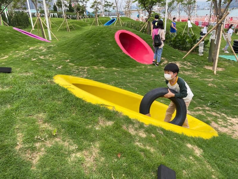 連接金鐘添馬和香港會議展覽中心的灣仔海濱長廊今日（五月七日）進一步開放，長廊靠近添馬公園的一端，設置了一個以「童樂園」為主題的活動區，藉着園境設計、高低起伏的草坪，配以色彩鮮艷的渠桶，於鬧市中營造天然風格的自由活動空間。