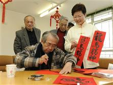 发展局局长林郑月娥正欣赏一位长者书写贺年挥春。