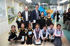 Mr Chan (back row, third left) and Mr Ma (back row, second left) are pictured with primary school students at the "Water: Learn & Conserve" Resource Hall in the Water Resources Education Centre.