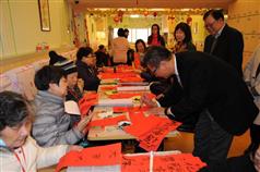Mr Chan (right) writes spring couplets during his visit to the day care centre. 