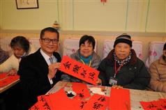 Mr Chan (left) presents a fai chun to elderly residents of the day care centre. 