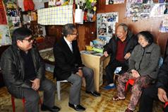 Mr Chan (second left) visits an elderly couple living in Pak Tin Estate and reminds them to keep warm during the cold weather.