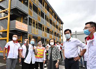 The Secretary for Development, Mr Michael Wong, and the Secretary for Food and Health, Professor Sophia Chan, visited the Kai Tak Community Isolation Facility this afternoon (May 27). Photo shows Mr Wong (second right), Professor Chan (third right), and the Director of Architectural Services, Ms Winnie Ho (centre), receiving a briefing on the facility from a staff member of the Architectural Services Department.