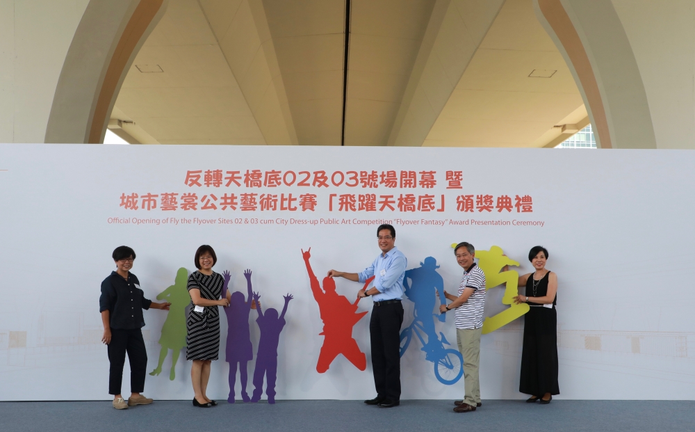 发展局局长黄伟纶（右三）与发展局常任秘书长（工务）韩志强（右二）、起动九龙东专员区洁英（左二）、建筑署副署长林余家慧（左一）和艺土民间主席杨肇珊（右一）主持“反转天桥底二、三号场”开幕仪式暨“城市艺裳公共艺术比赛－飞跃天桥底”颁奖典礼。