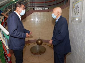 罗富国校友会前会长冯源（右）向发展局局长黄伟纶（左）介绍了学校另一个历史印记—傅科摆（Foucault Pendulum）。