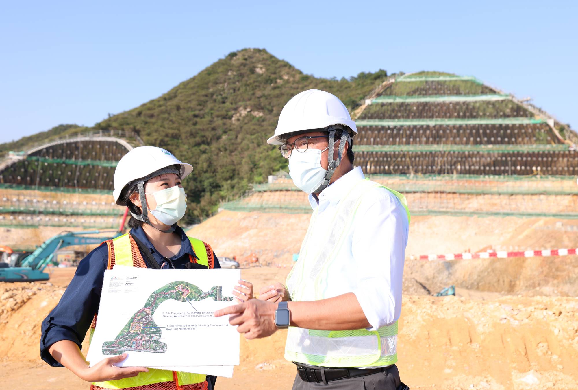发展局局长黄伟纶（右）听取土拓署北拓展处工程师陈晓彤（左）汇报，在古洞北新发展区兴建两个大型配水库的最新情况。
