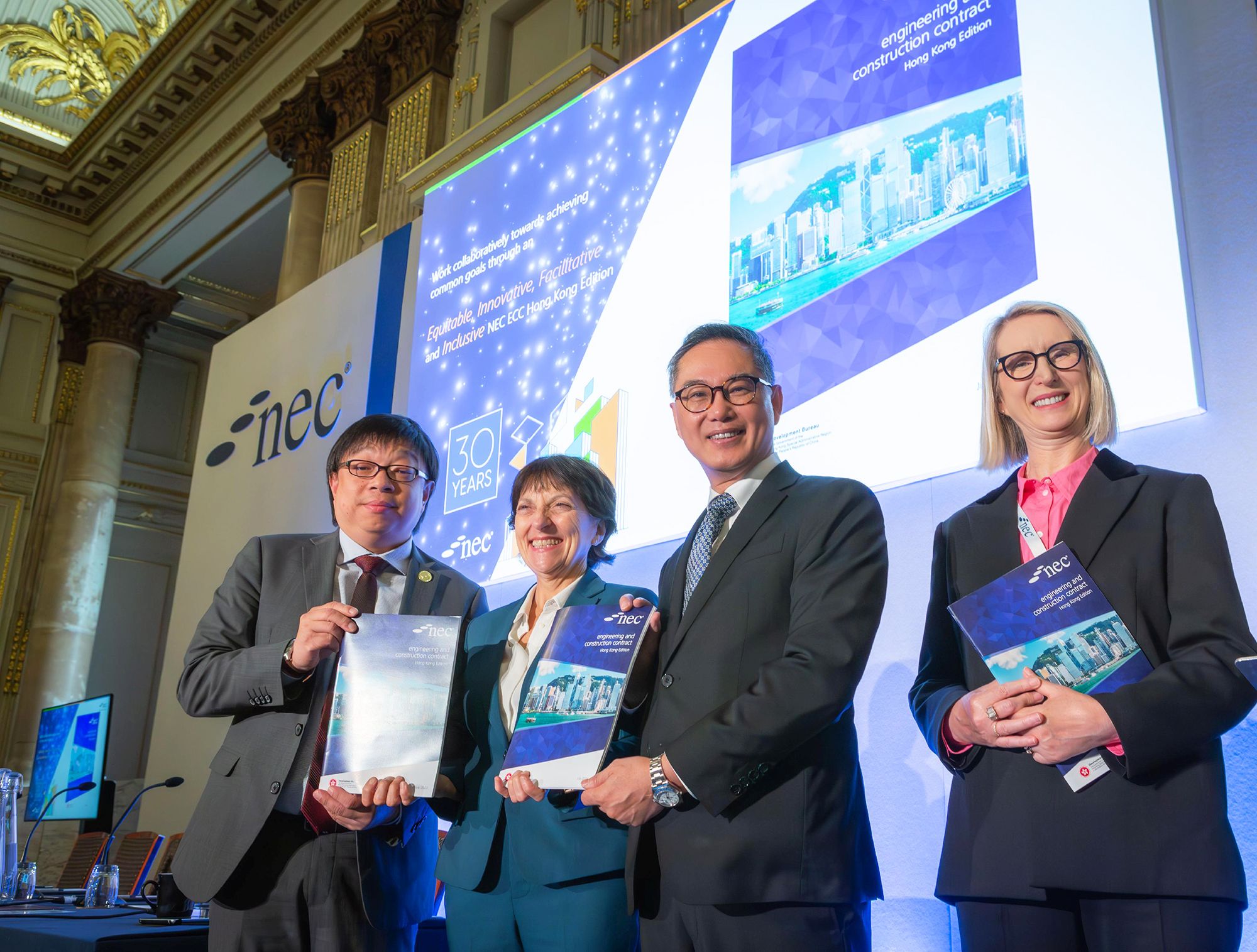 发展局早前在英国伦敦举行的「新工程合约」（New Engineering Contract-NEC）2023年度会议暨2023年度「Martin Barnes」奖项颁奖典礼上发布香港版「新工程合约─工程与建设合约」。图示发展局常任秘书长（工务）刘俊杰（右二）、发展局副秘书长（工务）何英杰（左一）、英国土木工程师学会总干事兼秘书长Janet Young博士（左二）等主持发布仪式。