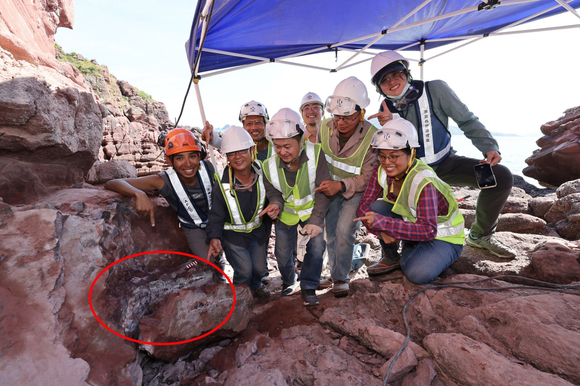 发掘团队与刚发现的恐龙化石（红圈范围示）。