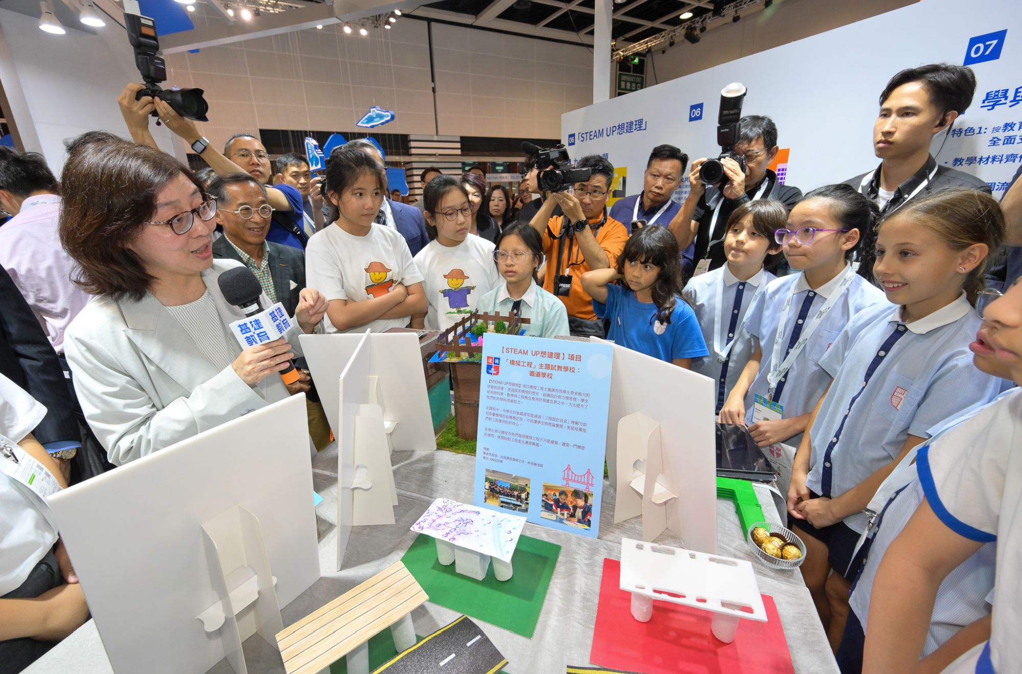 发展局局长宁汉豪（左一）与参展学校学生交流，并了解她们的创作。