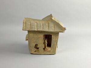 李郑屋汉墓出土曲尺式陶屋模型，屋后设小院圈养牲畜，屋内有人舂米，妇人抱子，是汉代百姓生活的写照。（古物古迹办事处藏）