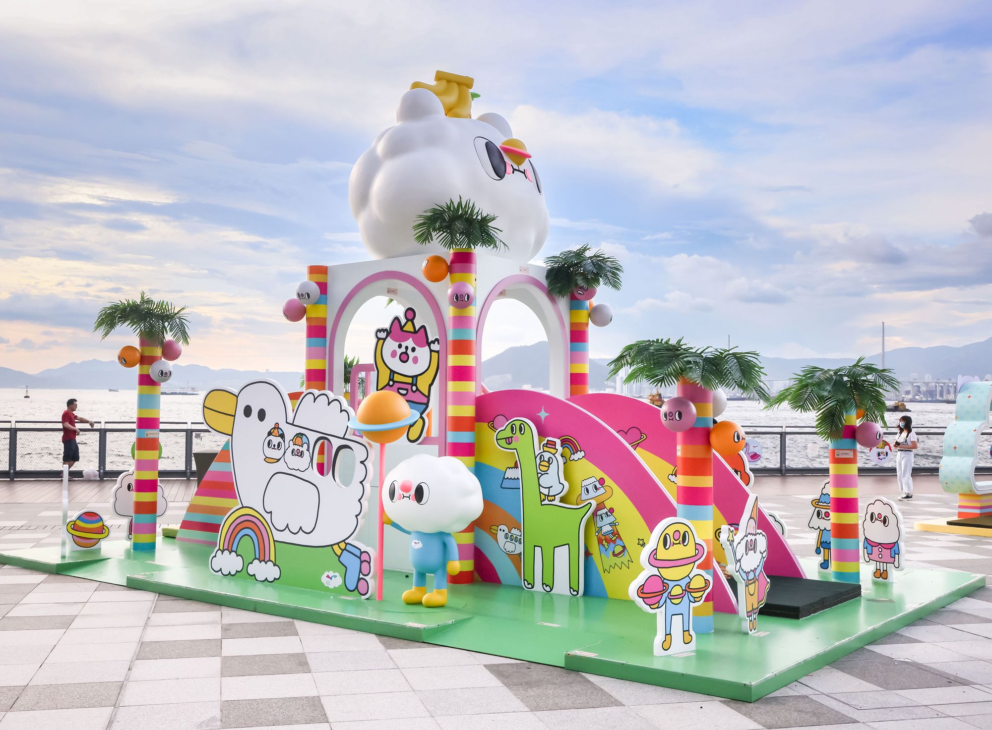 坚尼地城的卑路乍湾海滨长廊设有多个活动装置，包括「波萝油妹妹」的滑梯、凼凼转杯、摇摇板，以及「Messy Desk」的游乐设施。