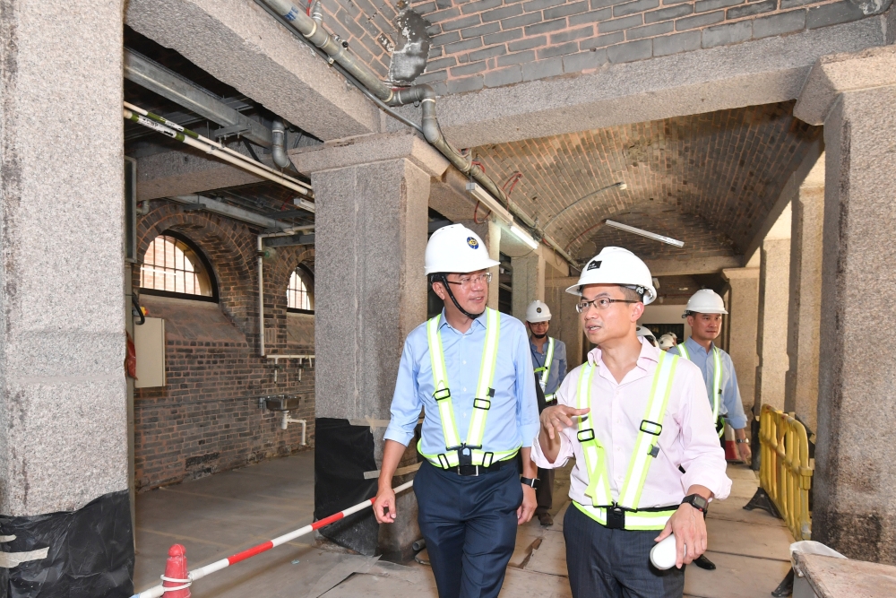 黃偉綸局長（左）聽取香港賽馬會慈善及社區事務執行總監張亮介紹中區警署建築群活化計劃的進展。