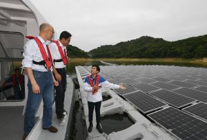 水務署助理電機工程師梁致峰（右）向兩名局長介紹安裝在船灣淡水湖的太陽能板系統，每年發電量可達12萬度，相當於36戶普通家庭的一年用電量，亦為地球每年減少84公噸的二氧化碳排放量。