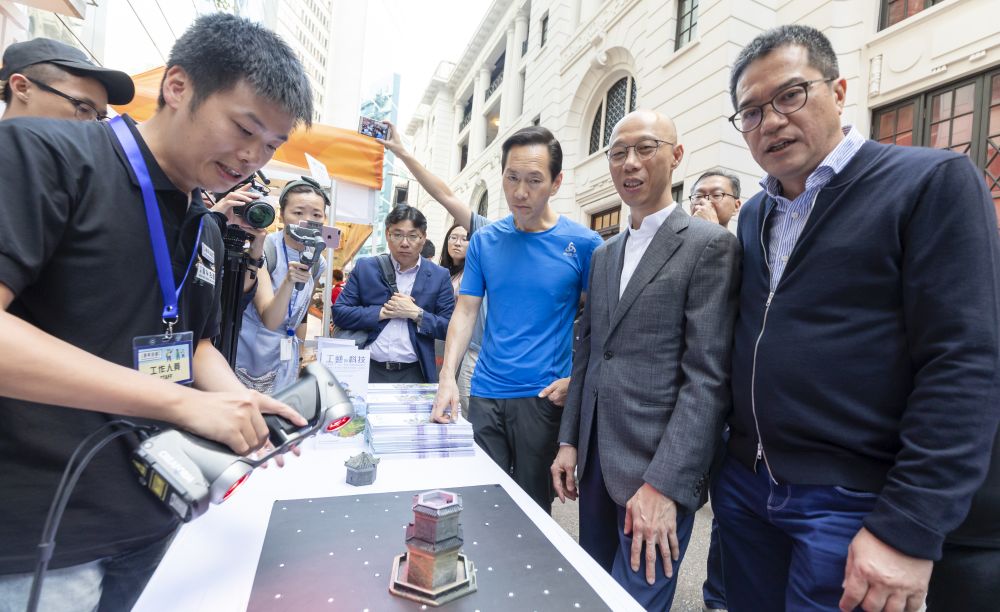 署理政務司司長黃錦星（右二）、行政會議召集人陳智思（右三）和發展局局長黃偉綸（右一）聽取古物古蹟辦事處工作人員講解如何透過三維激光掃描，協助進行文物保育工作。