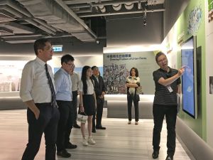 黃偉綸局長（左一）與兩位參加「與香港同行」計劃的中學生（左二及三）參觀市建局位於中環的社區空間H6 CONET，聽取市建局總監區俊豪（右）講解市區更新工作。