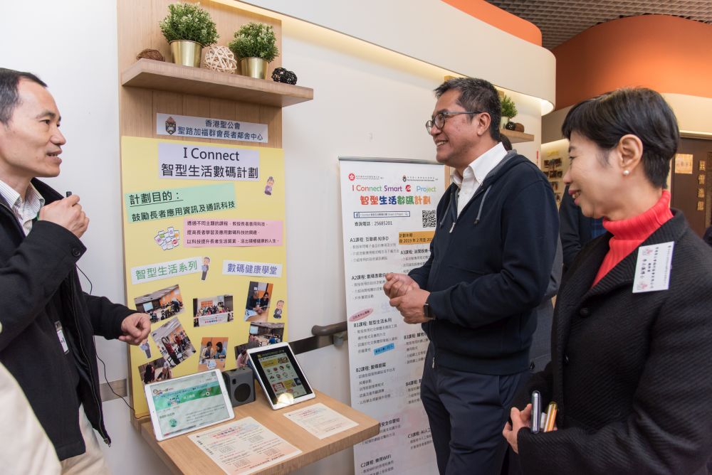 香港聖公會福利協會趙永盛（左）向發展局局長黃偉綸（中）介紹中心為長者提供的電腦訓練。