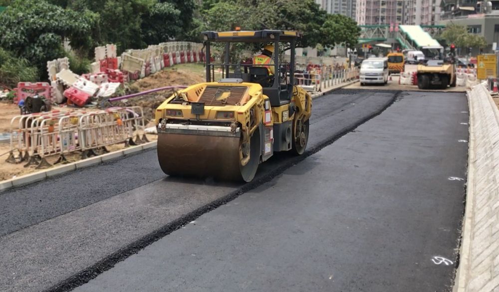 圖中工友正進行鋪設瀝青路面工程。由於內地採石場曾經停工，導致用於生產瀝青的碎石無法供應，因而影響相關工序。