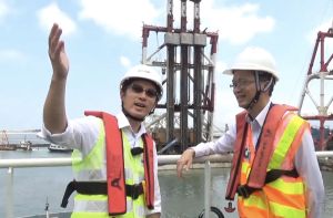 駐地盤高級工程師張建偉（左）向發展局副局長廖振新（右）介紹，「深層水泥拌合法」是以「攪拌」方式將工程船上的水泥注入海泥層，組合成「深層水泥拌合地層」來鞏固海床，以承托之後在上層建造的海堤及鋪設的填料。